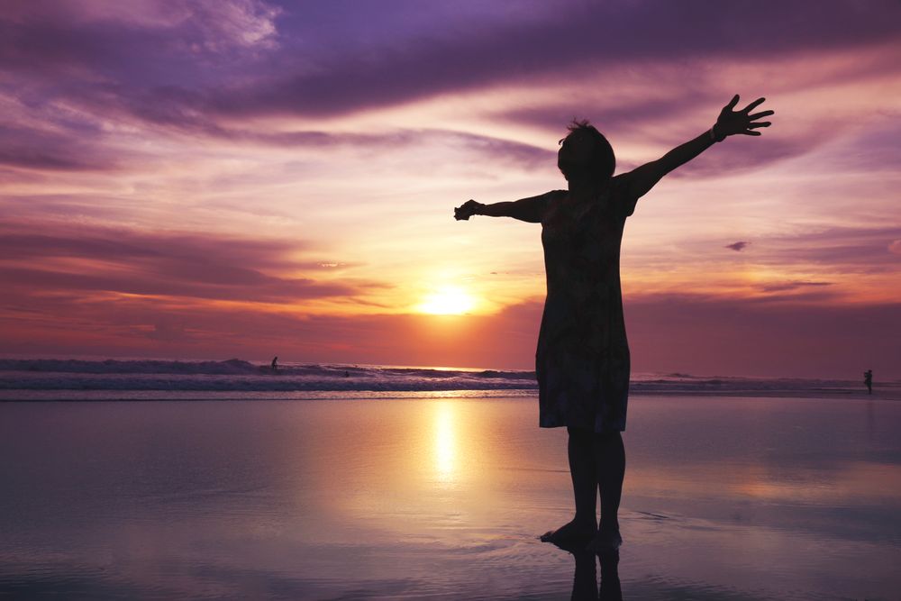 Person with arms outstretched at the beach