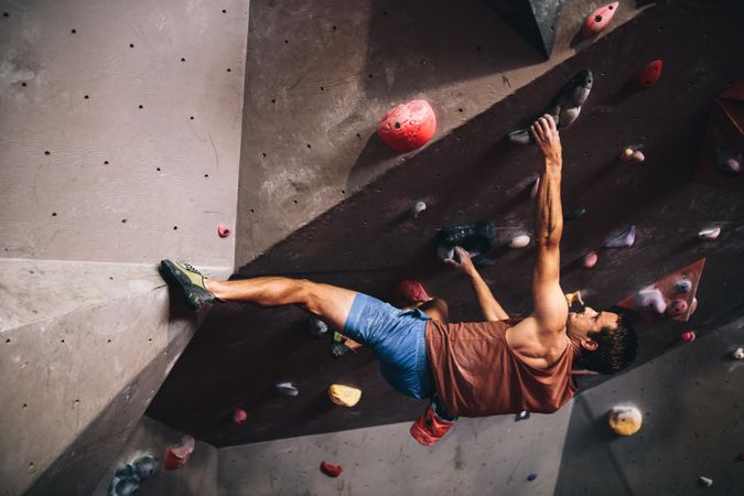 Skilled rock climber suspended off rock wall grips