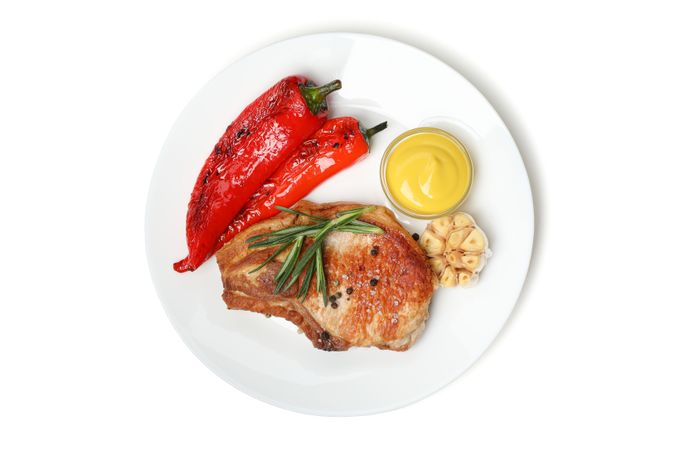 Plate with fried steaks and vegetables isolated on light background