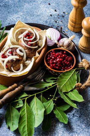 Georgian dish of abkhazura meat cutlets on plate with pomegranate seeds and bay leaves