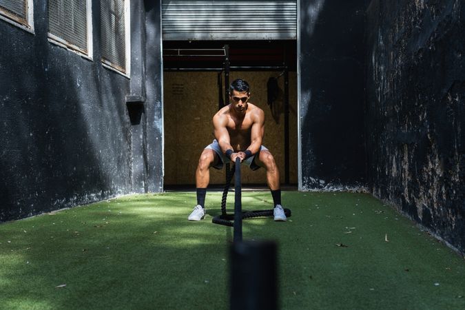 Muscular Hispanic sportsman pulling weight sled