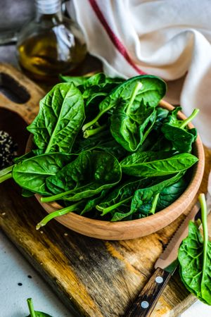 Wooden bowl of fresh spinach leaves on kitchen counter
