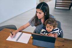 Mother taking notes while sitting with baby