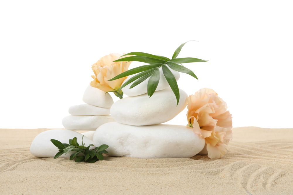 Stones, flowers and leaf on sand, isolated on plain background