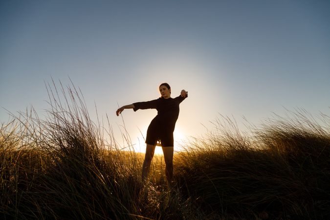 Woman posing between field at sunset