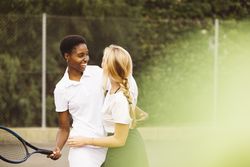 Portrait of two happy women in a tennis court