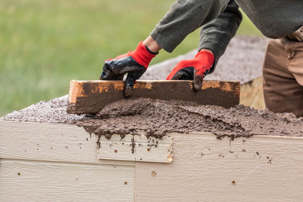 Construction Worker Leveling Wet Cement Into Wood Framing