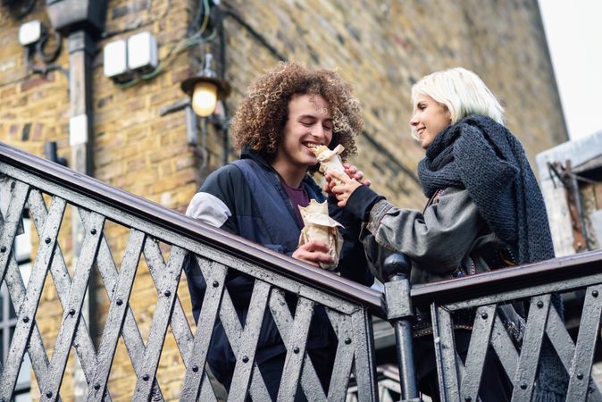 Couple sharing sandwich on fall day outside