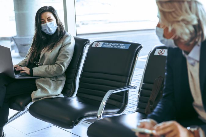 Business travelers wearing protective face masks waiting for their flights