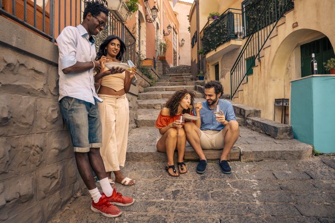 Group of friends eating pasta on the street in an Italian town