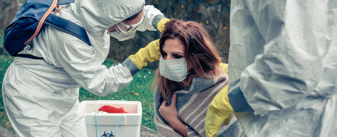 Doctors putting protective mask on woman infected with a virus