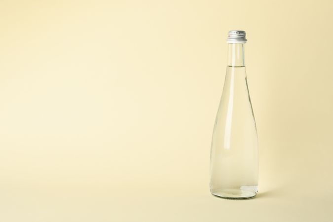 Glass water bottle in beige room with copy space