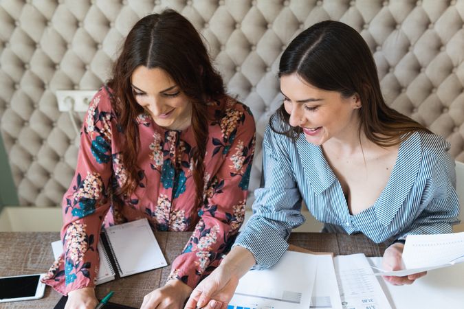 Crop focused female colleagues analyzing charts together in office