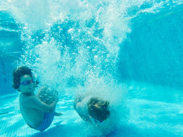 Excited kids under water in swimming pool