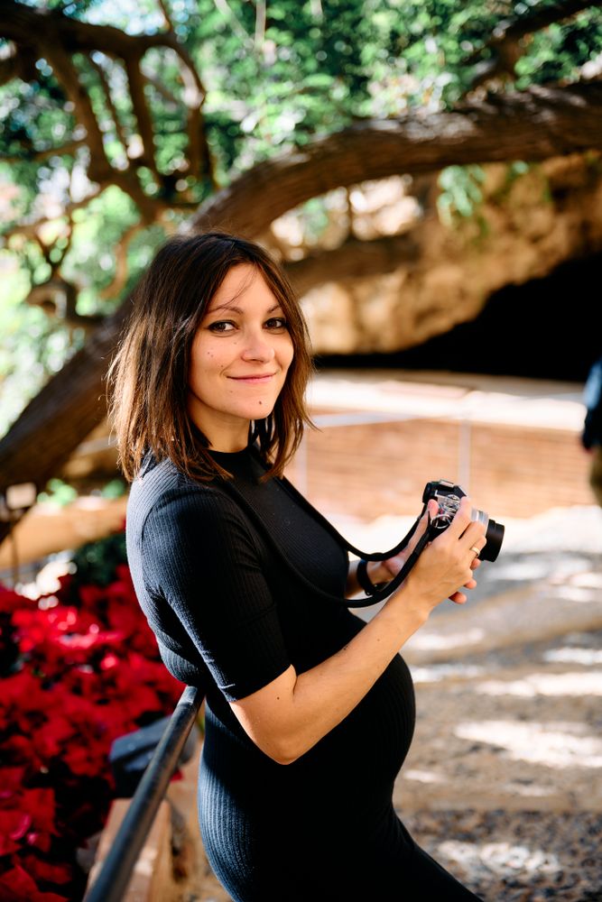 portrait of a young woman in a tight dress in her first months of pregnancy taking pictures with an antique camera