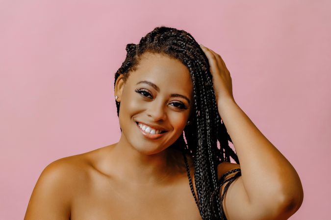 Female smiling and touching her hair in pink studio shoot