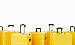 Yellow hard shell roller suitcases arranged on light background