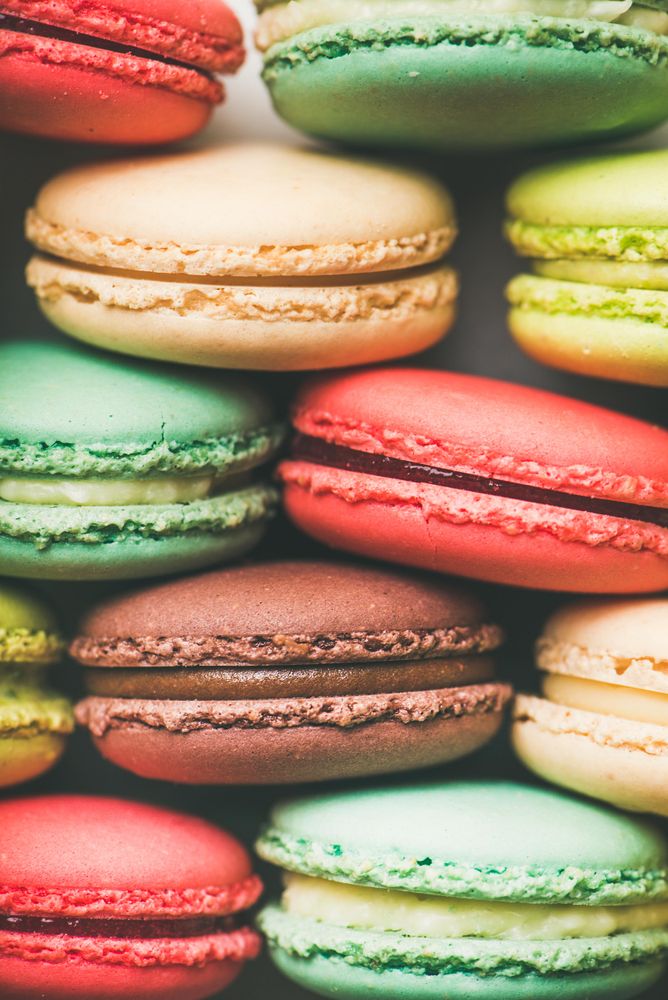 Bright multi-colored macaron pastries tightly stacked, side view, vertical composition, close up
