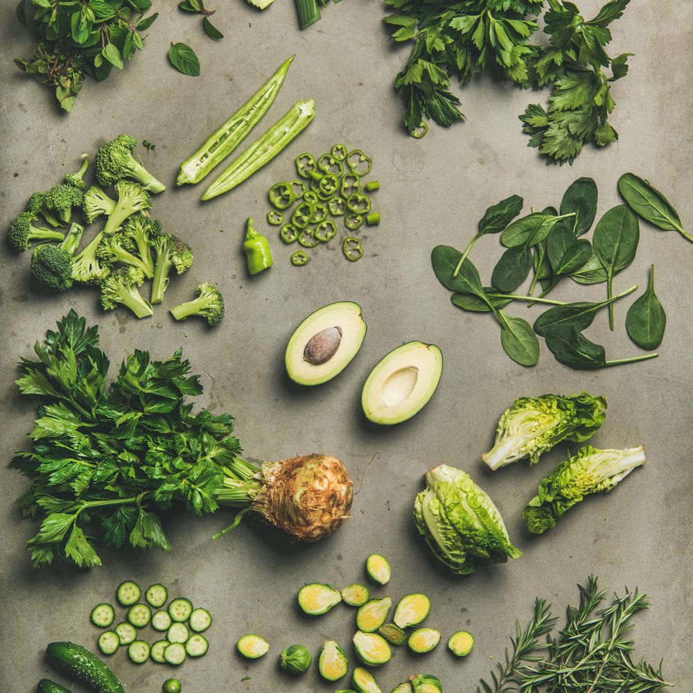 Arrangement of fresh green sliced garden vegetables on concrete surface, square crop