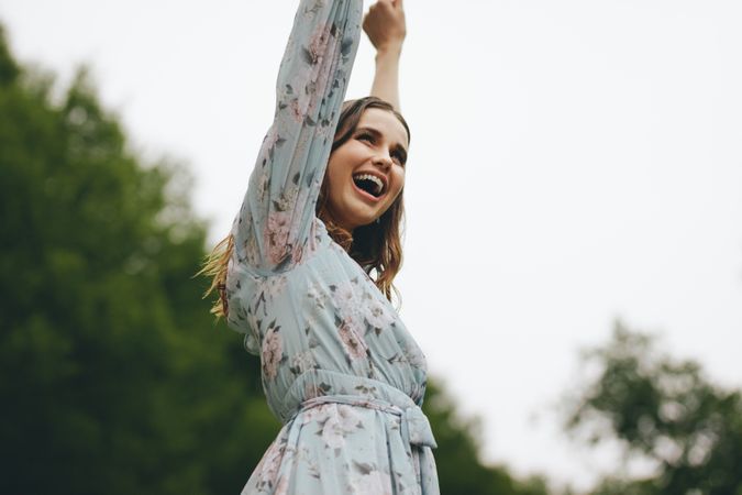 Cheerful woman standing at the park with her hands raised