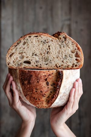 Crop person holding halved seeded bread