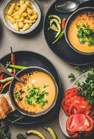 Yellow lentil soup bowls, vegetable garnishes, top view, vertical composition