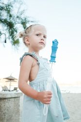 Little girl with bottle of soap bubbles at beach