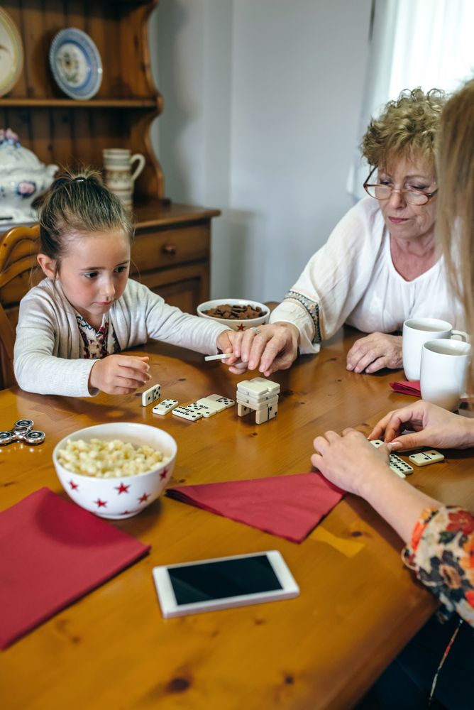 Three female generations playing with dominoes