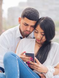 Man bonging smiling woman having fun with smartphone