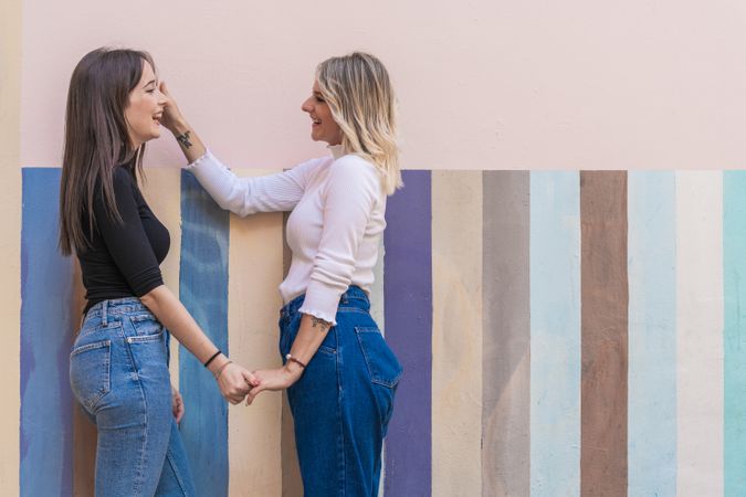 Happy girlfriends standing against painted urban wall