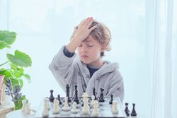 Focused preteen boy thinking over tactic while plying chess