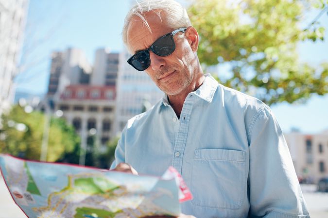 Older man consulting a map while touring a foreign city