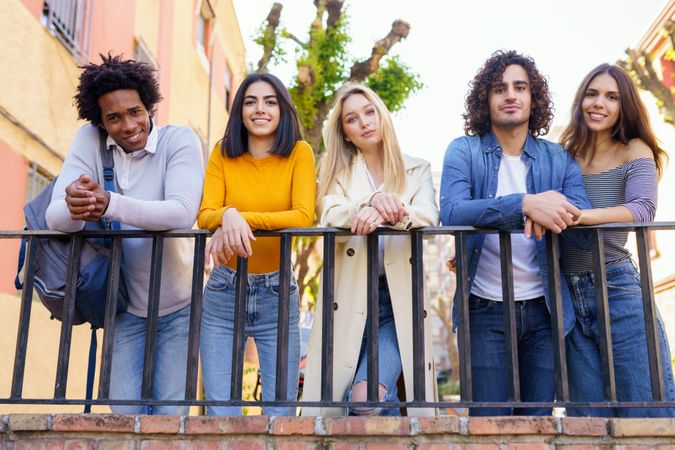 Portrait of happy male and female friends leaning on street railing