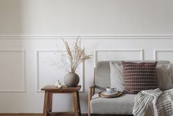 Dry grass bouquet in ball shaped vase, next to midcentury sofa with cup of coffee, checkered linen cushions & blanket