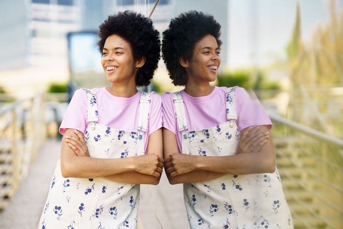 Happy female in floral overalls leaning on window outside