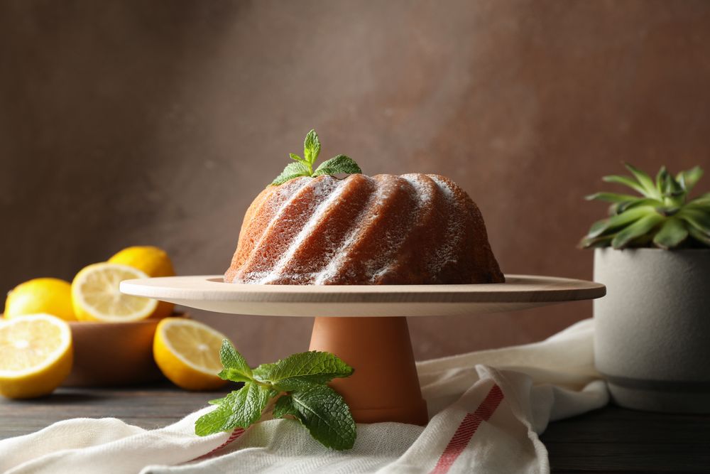 Cake with powder sugar and mint on wooden background, space for text