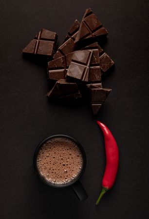 Chocolate near mug with hot drink and pepper