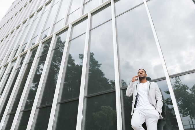Elegant Black man talking smartphone leaning building