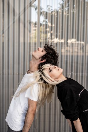 Loving man and woman supporting each other while standing back to back