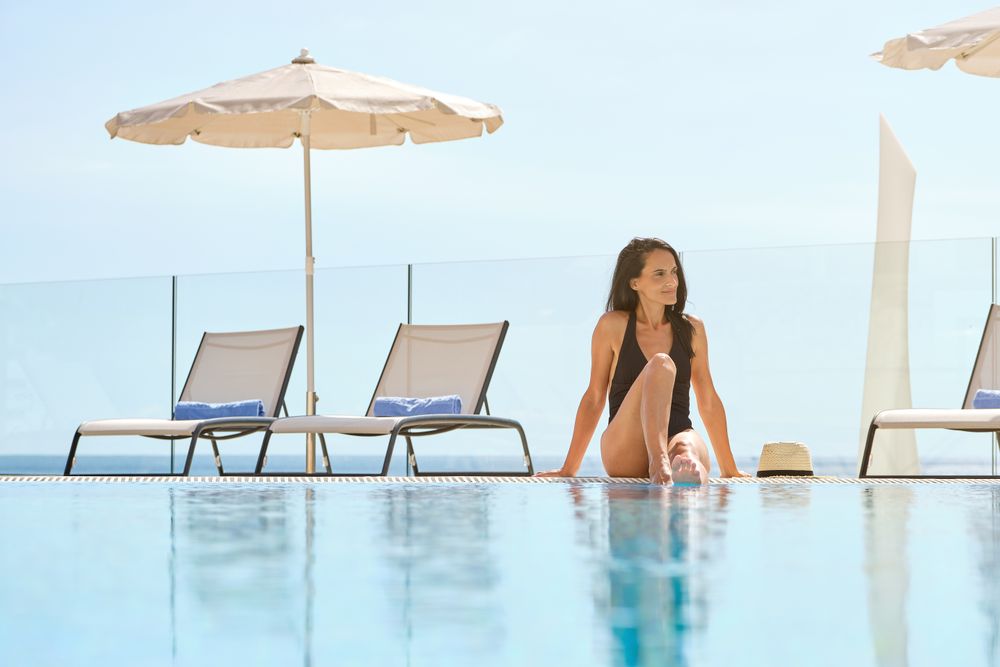 Content Hispanic female tourist in swimsuit resting on poolside