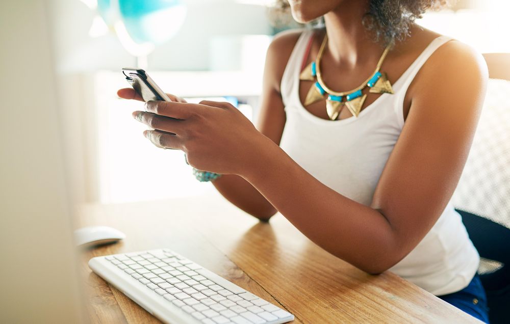 Woman in vest texting at desk