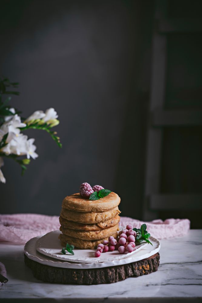 Pile of raspberry pancakes with honey on plate