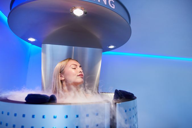 Woman in cryotherapy chamber with steam coming out over the top