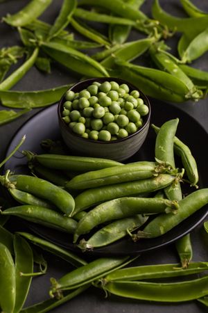 Fresh peas and pea pods on dark background