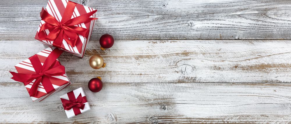 Merry Christmas with gifts and ball ornaments on weathered wooden background for the season