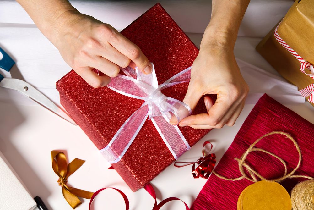 Person tying a red gift box