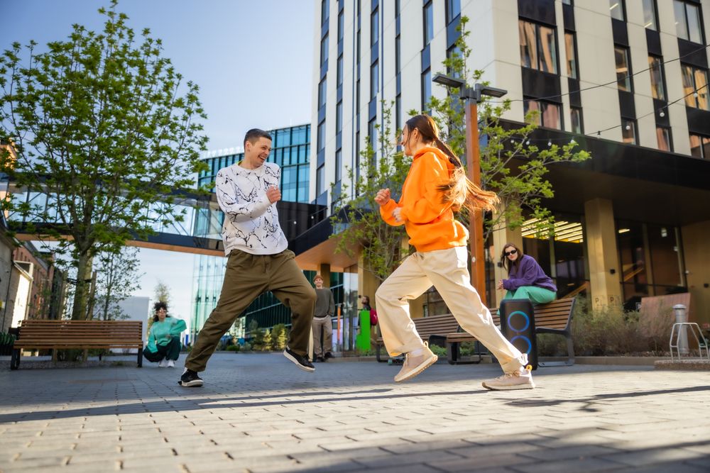 Vibrant Outdoor Scene Of Young Adults Joyfully Dancing On A Sunny Day