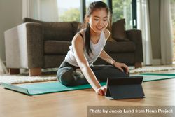 Smiling woman sitting exercise mat and watching training videos on digital table bDPnkb