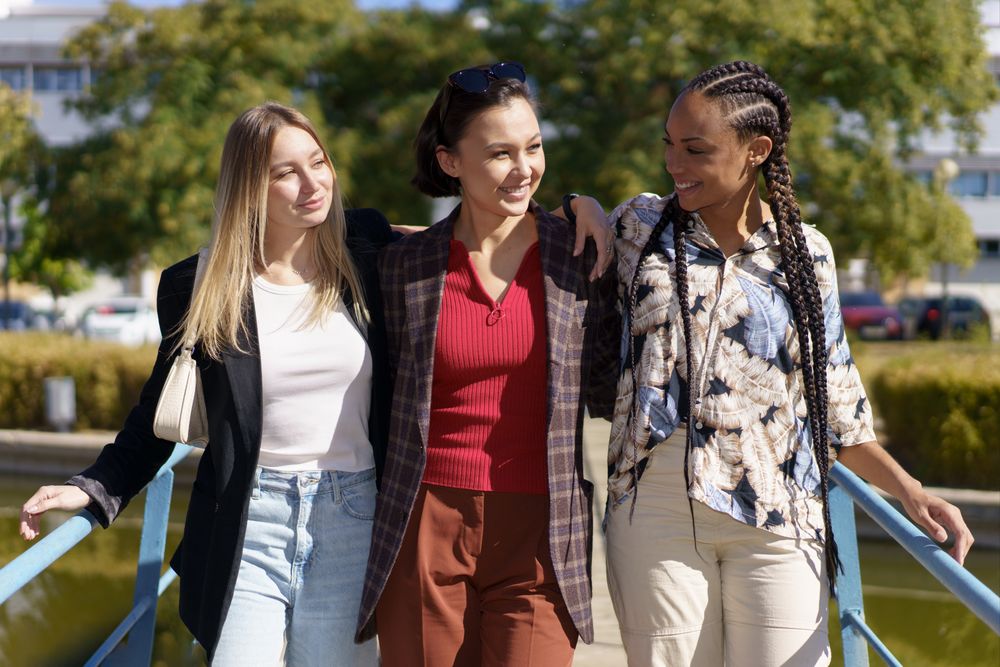 Three women walking over pedestrian bridge on summer’s day