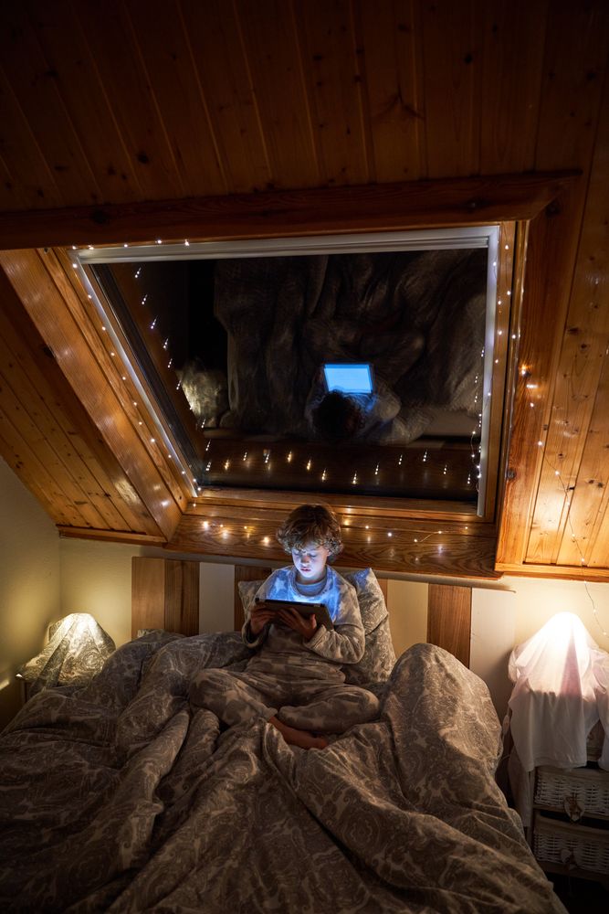Boy browsing tablet in dark bedroom